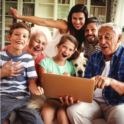 Bild mit einer Familie, die vor einem Laptop sitzen und lachen (Foto: Generation_241743884 - stock.adobe.com)